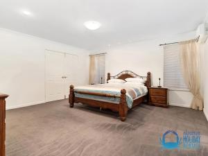 a bedroom with a bed and a dresser and window at Canal Elegance In Yunderup in Mandurah