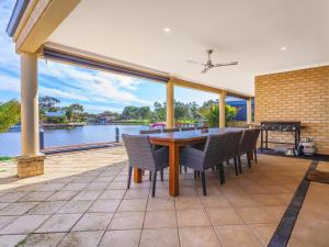 a table and chairs on a patio with a view of the water at Canal Elegance In Yunderup in Mandurah