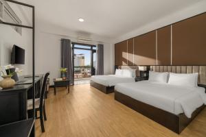 Una habitación de hotel con dos camas y un escritorio. en KLY Boutique Hotel Hue, en Hue