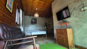a living room with a couch and a tv on a wall at Baan Job Sangkhlaburi in Sangkhla Buri