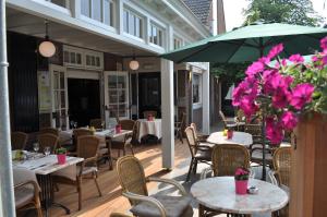 eine Terrasse mit Tischen, Stühlen und einem Sonnenschirm in der Unterkunft Hotel Boer Goossens in Den Dungen