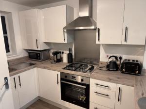 a kitchen with white cabinets and a stove top oven at Jakes Beach house in Hartlepool