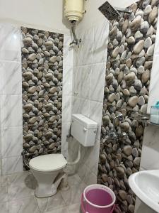 een badkamer met toilet en een rotswand bij Indore Home stay in Indore