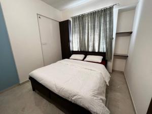 纳西克Anahat Host all Back Packer 2BHK 2 Bed AC的一间有窗户的小房间里的一张床