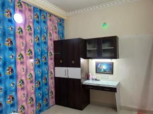 een kamer met een bureau en een keuken met een gordijn bij Indore Home stay in Indore