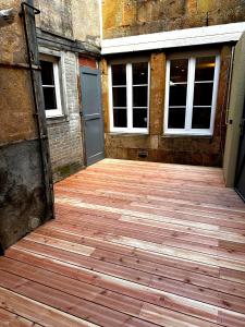 an empty wooden deck with a door and windows at Le Renaissance Appartement au cœur de Langres in Langres