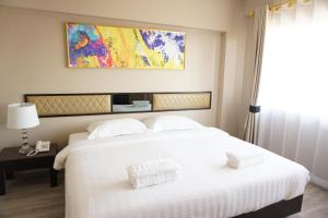 a large white bed with two white towels on it at Taris Art Hotel Phrae in Phrae +52 photos