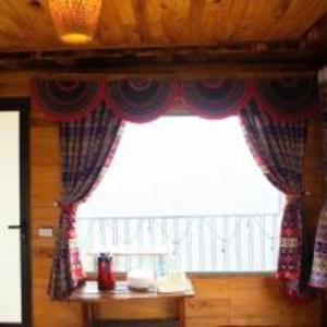 a window with curtains and a table in a room at Mây Homestay - Venuestay in Trạm Tấu