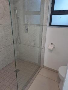 a bathroom with a shower with a glass door at Beach Walk Cottage in Plettenberg Bay