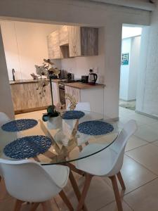 a kitchen with a glass table and white chairs at Beach Walk Cottage in Plettenberg Bay +6 photos