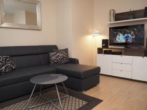 a living room with a black couch and a tv at Grand-Tourist Posejdon Apartments in Gdańsk