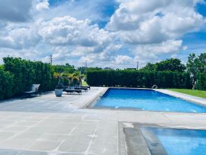 a swimming pool in a yard with chairs and trees at H&K Guest House in Urdaneta