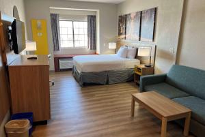 a hotel room with a bed and a couch at Days Inn by Wyndham near Kansas Speedway in Kansas City +20 photos