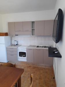 a kitchen with white appliances and a table and a television at Casa relax Berchida in Capo Comino +10 photos