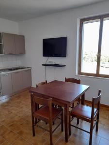 a kitchen with a wooden table and chairs and a television at Casa relax Berchida in Capo Comino