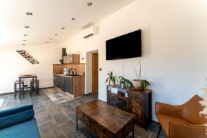 Una sala de estar con un sofá y un televisor en una pared. en Mas de l'Acqueduc, en Le Barroux