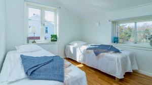 two beds in a white room with two windows at Villa Sjöbris - Lake Vänern in Ängenäs