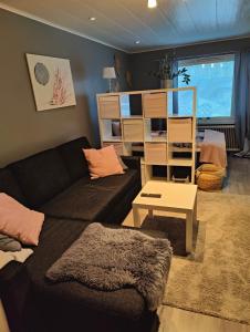 a living room with a black couch and a desk at Viihtyisä yksiö Porissa in Pori