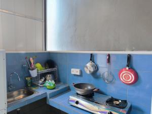 a blue tiled kitchen with a stove and utensils at Kubu Alit Homestay Pandawa in Nusa Dua