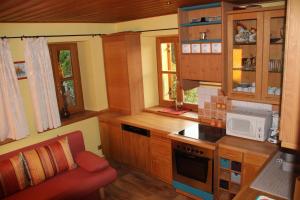 a small kitchen with wooden cabinets and a red chair at Ferienwohnung Edelweiss in Bischofsgrün