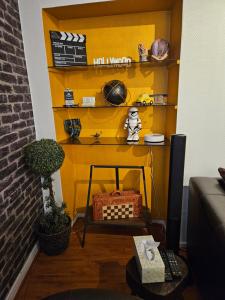 een woonkamer met een gele muur en een plank bij "Studio Cinéma" -Coeur de ville- Spacieux, calme et connecté-alexa, wifi, free, netflix, disney, prime video, jeux vidéo et de société in Auxerre +18 foto's