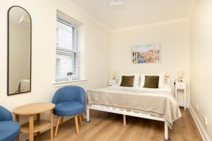 a bedroom with a bed and two blue chairs at JOIVY Lovely Flats near the City Centre in Edinburgh