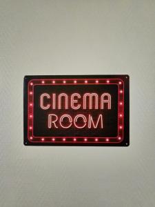 een neonbord met filmzaal op een muur bij "Studio Cinéma" -Coeur de ville- Spacieux, calme et connecté-alexa, wifi, free, netflix, disney, prime video, jeux vidéo et de société in Auxerre