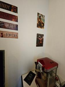 een kamer met een tafel met een rode blender en foto's aan de muur bij "Studio Cinéma" -Coeur de ville- Spacieux, calme et connecté-alexa, wifi, free, netflix, disney, prime video, jeux vidéo et de société in Auxerre