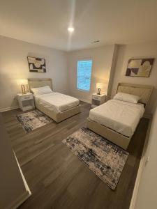 two beds in a bedroom with two rugs at Modern comfort house in Madison