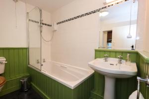 a green and white bathroom with a sink and a tub at Bronfelin & Troed-y-Rhiw Holiday Cottage in Llanwrtyd Wells