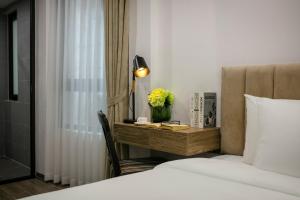 a hotel room with a bed and a desk with flowers at Emissary Corner Hanoi Hotel & Spa in Hanoi