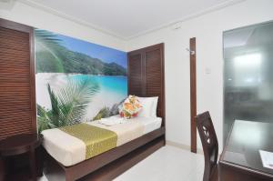 1 dormitorio con 1 cama y una pintura de playa en 717 Cesar Place Hotel en Tagbilaran City
