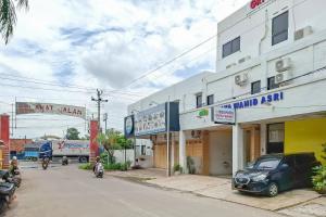 a street with cars parked in front of a building at RedDoorz Syariah at Griya Wahid Alun Alun Batang in Batang