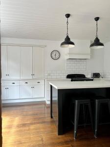 a kitchen with white cabinets and a clock on the wall at Charming Heritage Home in Launceston +14 photos