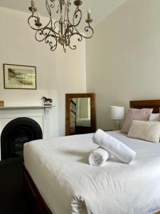 a bedroom with a large white bed with a chandelier at Charming Heritage Home in Launceston