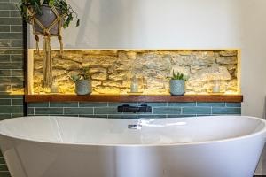 a bath tub in a bathroom with two potted plants at La Gaillardenque Gîtes - Farmhouse and Gîte in Floressas +50 photos
