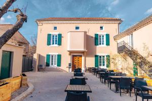 a courtyard with tables and chairs in front of a building at La Sousto de Lili in Rasteau