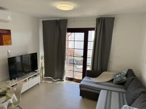 a living room with a couch and a television at Castillo Sol Bungalow in Caleta De Fuste