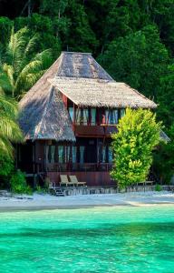 ein Haus mit Strohdach am Strand in der Unterkunft Yenatar Resort in Friwin