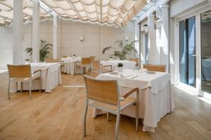a dining room with white tables and chairs at NH Collection Marbella in Marbella
