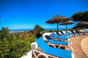 a row of chairs with umbrellas and the ocean at Three bedroom apartment La Mairena Elviria in La Mairena
