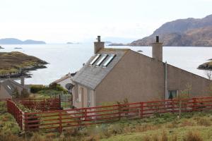 a house with a red fence next to a body of water at Shiant View in Lochs