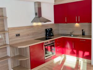 a kitchen with red cabinets and a sink at Alpinum - die Ferienwohnung in Bad Hindelang