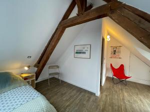 a bedroom with a bed and a red chair at Longère cœur de village proche des plages in Sassetot-le-Mauconduit