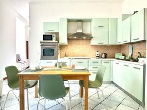 a kitchen with white cabinets and a wooden table and chairs at Over the Rainbow in Sant'Agnello +6 photos
