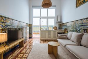 a living room with a couch and a tv at Apartamentos "El Escondite de Triana" in Seville