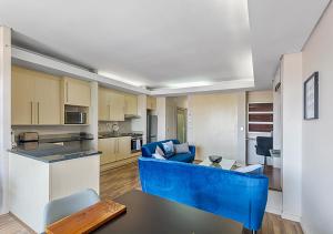 a living room with a blue couch and a kitchen at Stylish Genisis on Fairmount U15 in Johannesburg