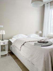 a white bedroom with a white bed and a window at Sunny Beach Apartment Hiekkasärkät Kalajoki in Kalajoki