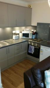 a kitchen with a stove top oven and a microwave at 4B Wentworth Street Apartment in Portree