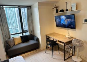 a living room with a desk and a couch and a table at Greenbelt with Wifi, Pool and Gym in Manila